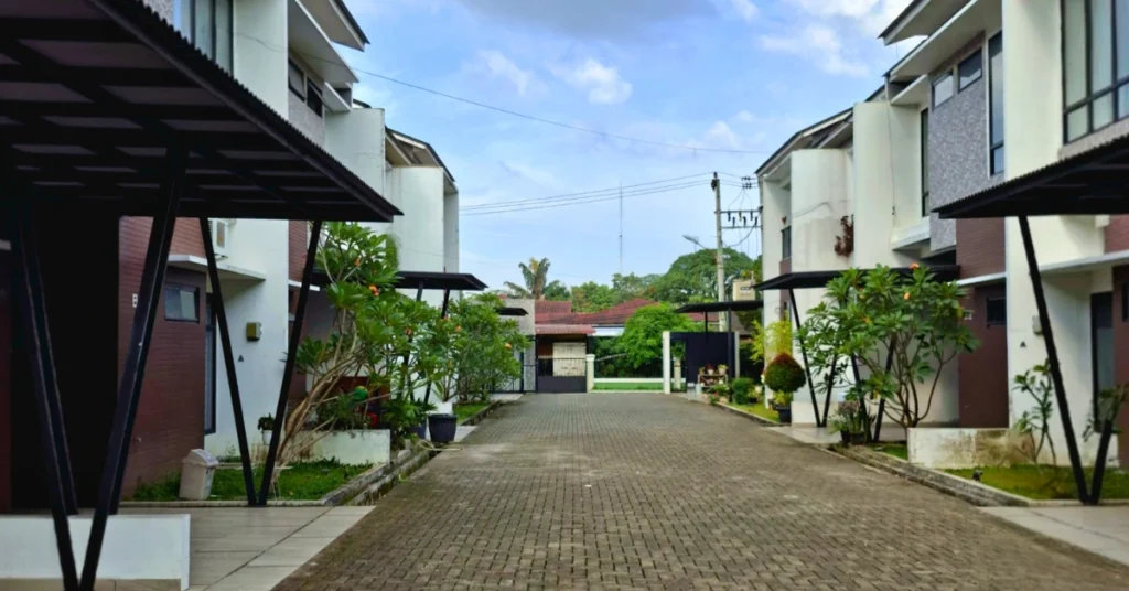 Pemandangan jalan lingkungan di dalam cluster perumahan yang rapi, menampilkan deretan rumah dijual di Medan dengan desain minimalis dua lantai.